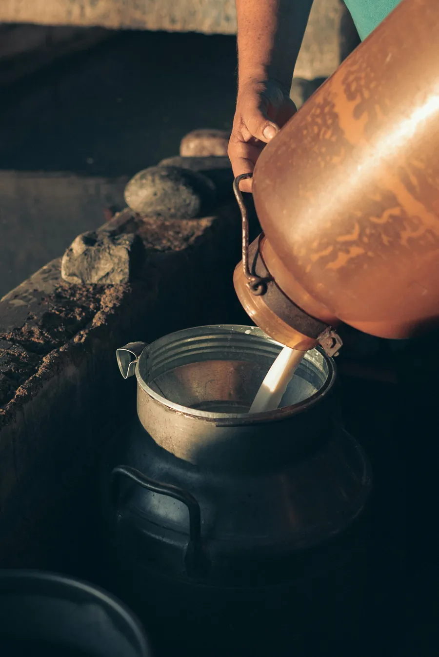 Milk being poured from a copper vessel